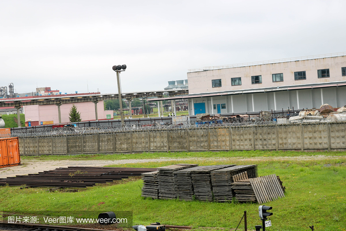 在一个工厂里,露天街道上的草地上堆放着一堆木托盘